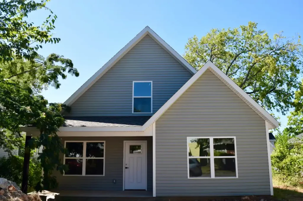 Modern gray house with trees and blue sky.